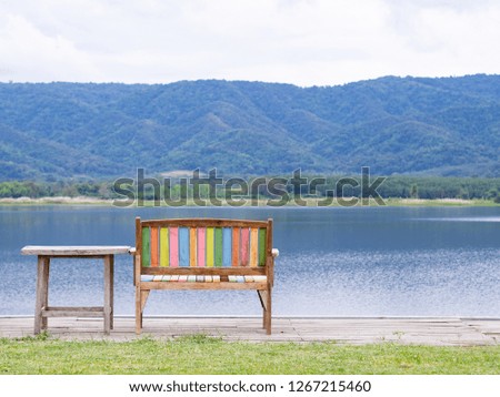 Back view of wooden chair and table to relaxing for looking at view lake and beautiful nature mountains. Scenic view landscape of lake and mountains in Northern Thailand. Space for text.