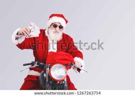 Santa Claus with a white beard wearing sunglasses and Santa outfit sitting on the motorcycle with a Santa bag and holding a lot of money, New Year, Christmas, holidays, souvenirs, gifts, shopping