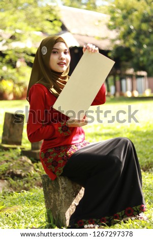 Women wearing hijab holding empty sign board. Malay traditional concept. Modest fashion style.