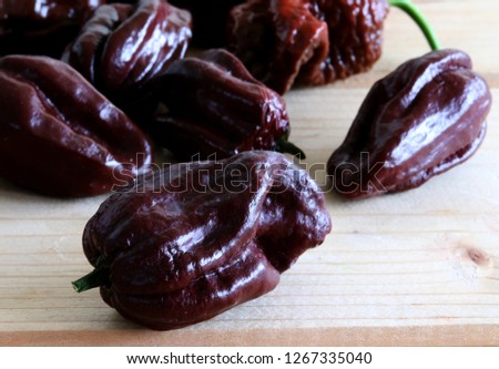 Group of ripened capsicum chinense very hot peppers on wooden table, Habanero chocolate. Picture design for foods background.