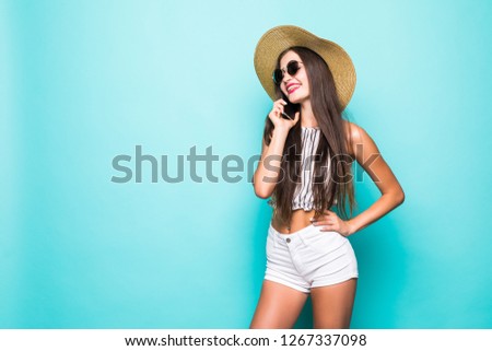 Beautiful laughing woman in summer hat talking on mobile phone on blue background