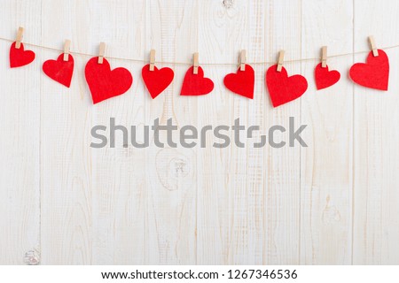 Red hearts on rope with clothespins, on a white wooden background. Place for text, copy space. Royalty-Free Stock Photo #1267346536