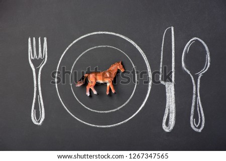 Toy brown horse on a plate in the figure on the chalk board