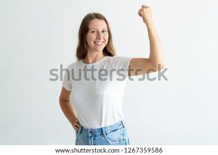 Cheerful young woman pumping fist and celebrating achievement. Pretty girl looking at camera. Achievement concept. Isolated front view on white background.