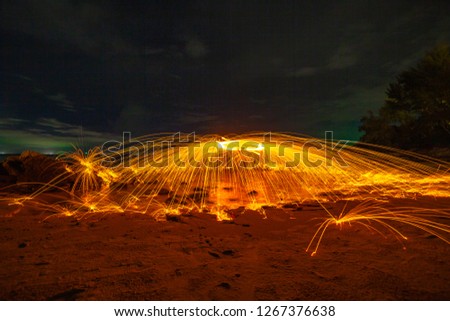 
cool burning steel wool art fire work photo experiments on the beach at sunset
