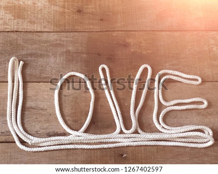 Pile of gray rope on empty old wood, Arranged as shaped the letters "love", with lens flare, in dark tone. With space for your text design, rural style. Valentine's concept. Top view.