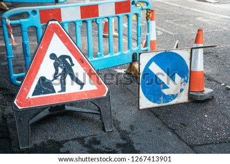 Under construction board sign on the closed road with arrow sign and traffic cone. Caution symbol under construction, work in progress sign. Royalty-Free Stock Photo #1267413901