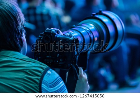 Journalist photographer with a telephoto lens at work, back view
