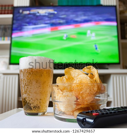 APPETIZER OF FRIED POTATOES AND BEER SEEING FOOTBALL MATCH Royalty-Free Stock Photo #1267429657