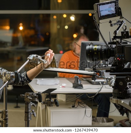 Behind the scenes of the camera when shooting a film, advertisement, video, team, actors. Shooting place, side view, focus on the hand with a raised finger.