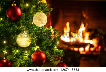 Christmas time, warm home. Christmas tree close up on blurred burning fireplace background, copy space