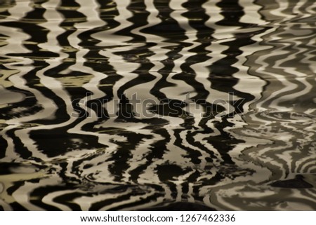 Silk water surface with golden stripes and waves, background textural image