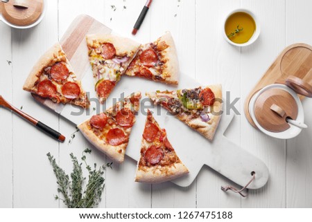 Hot Italian pizza with melting tomato,pepperoni and cheese on a white rustic wooden table.