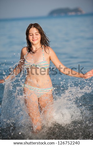 Young teen girl playing with waves at the beach.