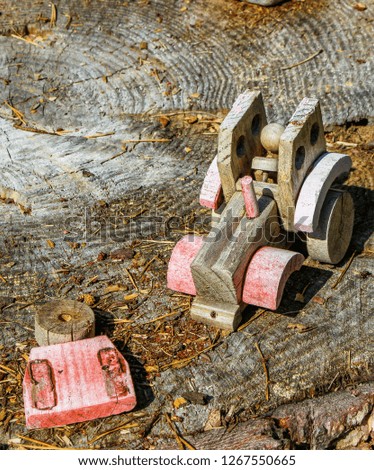 Broken wooden toy car on a pine stump with memories of childhood