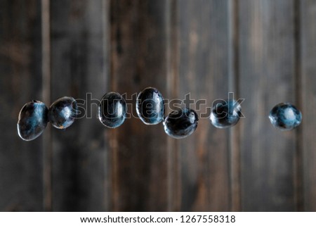 dark blue grapes flying and falling in air on a wooden background