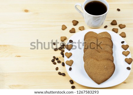 Heart shaped cookies and black coffee close up on wooden background. Place for text. Breakfast for Valentine's day.