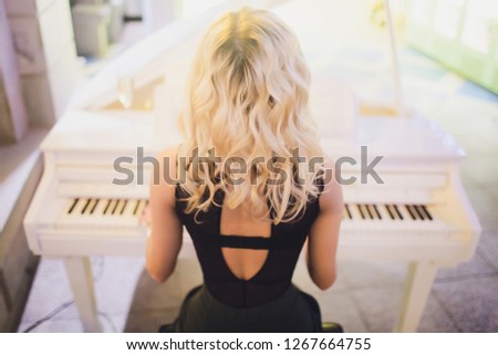 Beauty Blonde Woman Portrait. Beautiful bride with long curly blond hair sitting at the piano. White Hair. Perfect Skin and Make up. Hair Extensions.