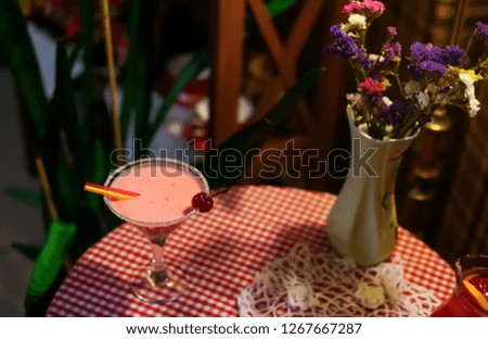 Rose milk fruit berry alcoholic or soft coctail on a checkered table cloth with a vase with flowers, country style cafe