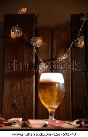 Christmas beer in a glass on a wooden background with light bulbs and Christmas toys