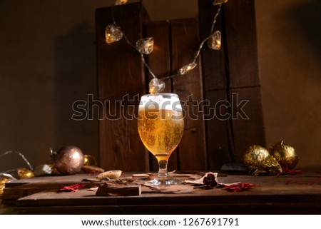 Christmas beer in a glass on a wooden background with light bulbs and Christmas toys