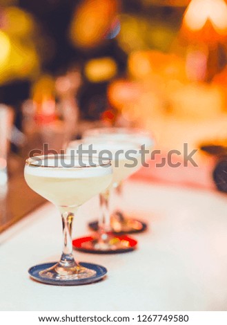 White Cocktail drinks-beverage on  a bar.  Selective focus on the foreground glass,night background . Blurred people in the background.  Trendy black stylish  edit. Copy paste space for design concept