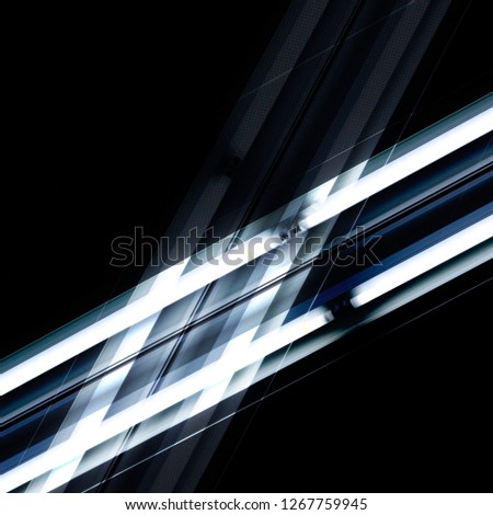 Daylight ceiling lamps glowing in darkness. Abstract background on the subject of modern architecture / interior, industry, energy saving and power technology. Geometric structure of parallel lines.
