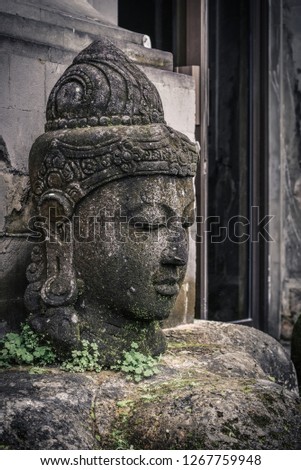 Stone Buddha head statue  in garden on Bali island, Indonesia