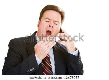 Businessman talking on his cellphone is yawning from boredom and exhaustion.  Isolated on white.