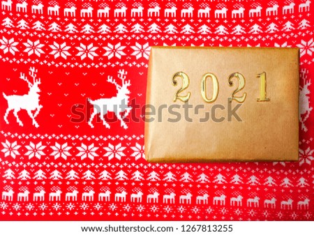 Christmas gifts and numbers 2021,  christmas pattern - Christmas tree and deer.  red background, top view. present box wrapped in craft brown paper.  happy new year. 
