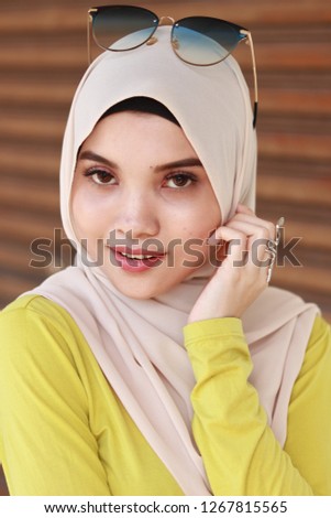 Beautiful and cute young Asian portraiture at street outdoor. Hijab cream color fashion.