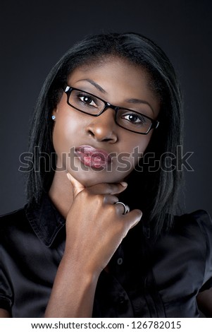 Portrait of a young businesswoman with hand on chin over black background