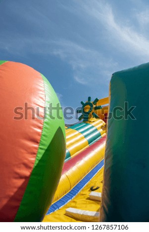 A giant colorful inflatable slider with joyful kids running up and down the slider in the fun park with happiness.