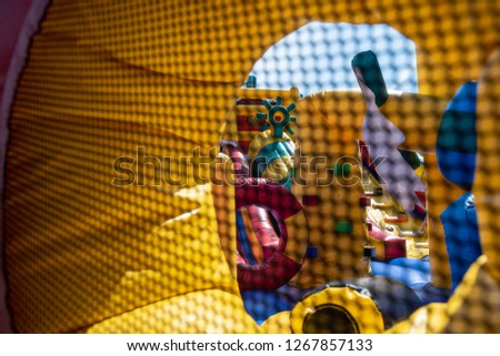 A giant colorful inflatable slider with joyful kids running up and down in the fun park with happiness and excitement.