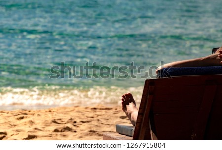 Enjoy and relax Caucasian woman wear sunglasses lying and sunbathing on sunbed at sand beach for make tan skin at paradise tropical island. Summer vacation on the beach. Holiday travel agent concept.