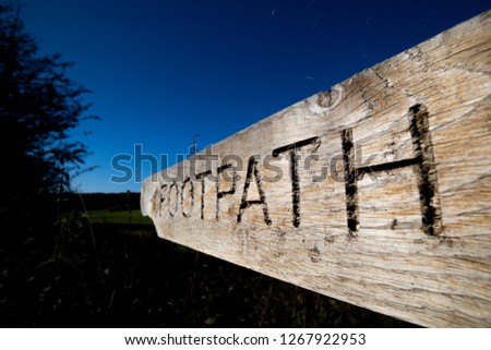 Wooden footpath sign showing right of pedestrian way across farmland in rural Hampshire