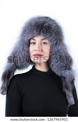 Beauty portrait of a cute girl with big lips in a black jumper and a gray Fox fur hat with long ears