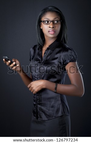 Young business woman holding cellphone and looking away over black background