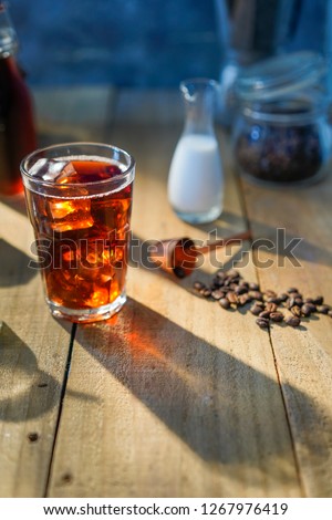 Setup ice coffee americano in a glass on wood table with sugar, milk.