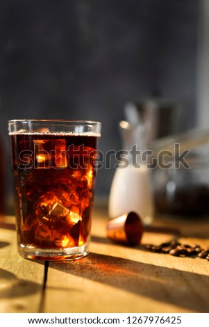 Setup ice coffee americano in a glass on wood table with sugar, milk. 