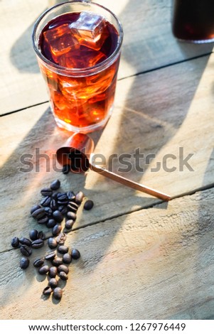 Setup ice coffee americano in a glass on wood table with sugar, milk.
