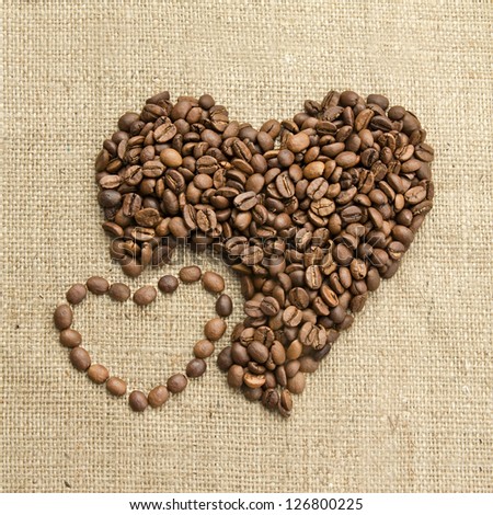Coffee beans, grain two hearts on background of sacking, bagging. Valentine's Day or Wedding, love, black, frame. Heart shaped Coffee Beans. Big and small heart. Retro