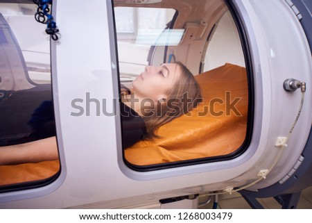 a girl in a black T-shirt lies in a hyperbaric chamber, oxygen therapy, a medical room Royalty-Free Stock Photo #1268003479