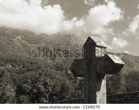 old stone cross near the church in front of the beautiful wild mountain panorama