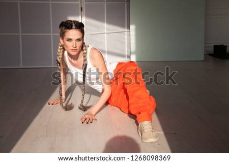 beautiful fashionable woman with braids dancing work overalls