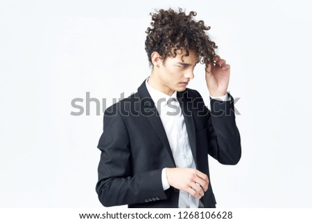 Curly guy in a classic suit and earrings touches the hair with his hands                      
