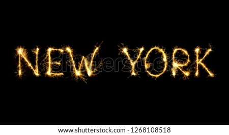 The city's name New York is written in sparklers fireworks. Beautiful Sparkling word New York isolated on black background. Glowing overlay text template for design