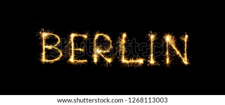 Berlin text handmade written sparkles fireworks. Beautiful Sparkling word Berlin isolated on black background. Glowing overlay template for design Royalty-Free Stock Photo #1268113003