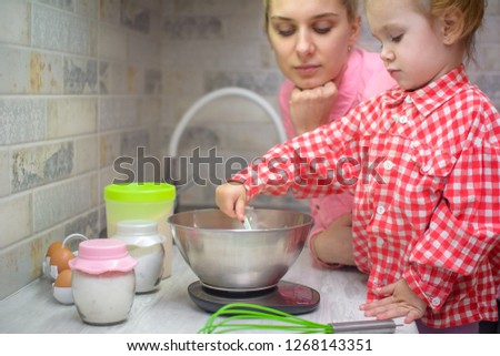 happy family in the kitchen. mother and child daughter preparing the dough, bake cookies. adorable child with mother  making dough with flour and egg together at home 