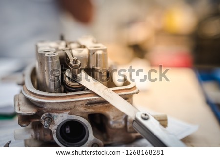Motorcycle mechanic using a Feeler Gauge tool service tuning engine's valve , wrench and socket on the engine of Motorcycle , (maintenance) Royalty-Free Stock Photo #1268168281
